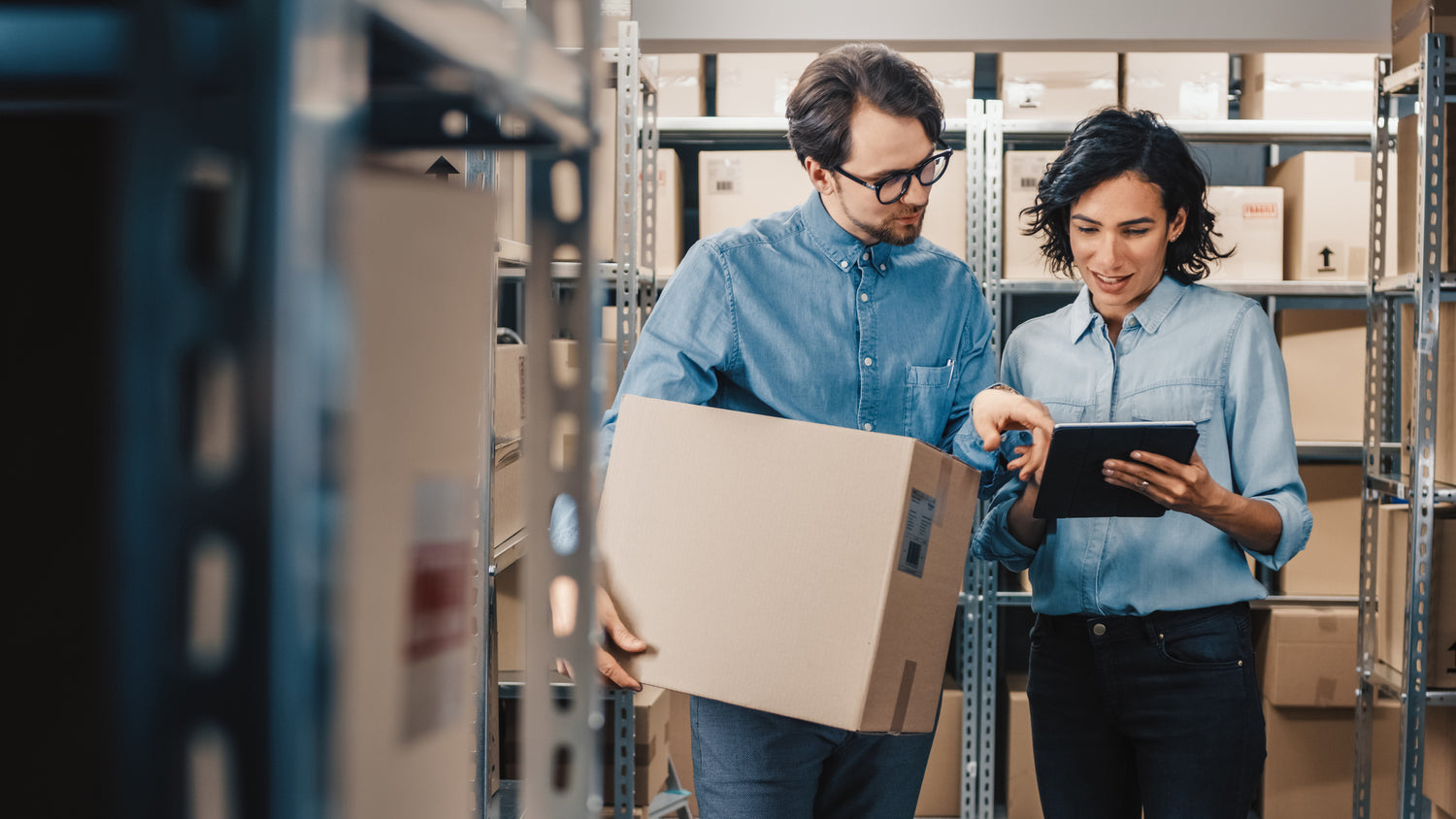 man and woman looking at tablet holding a box